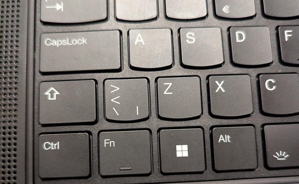 A laptop keyboard, with a shift key to the left of a key with the characters ><|